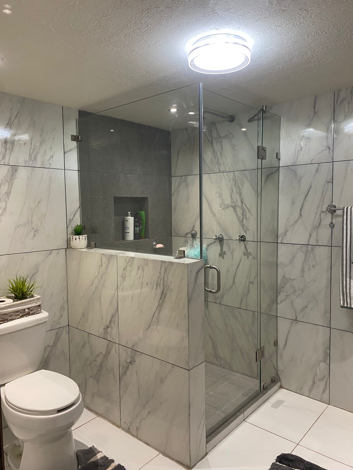 Cancel de cristal templado en baño con acabados de mármol